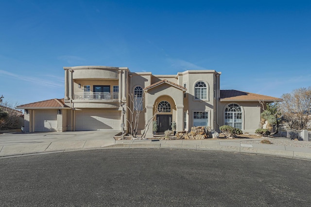 view of front of home featuring a tiled roof, driveway, a balcony, and stucco siding