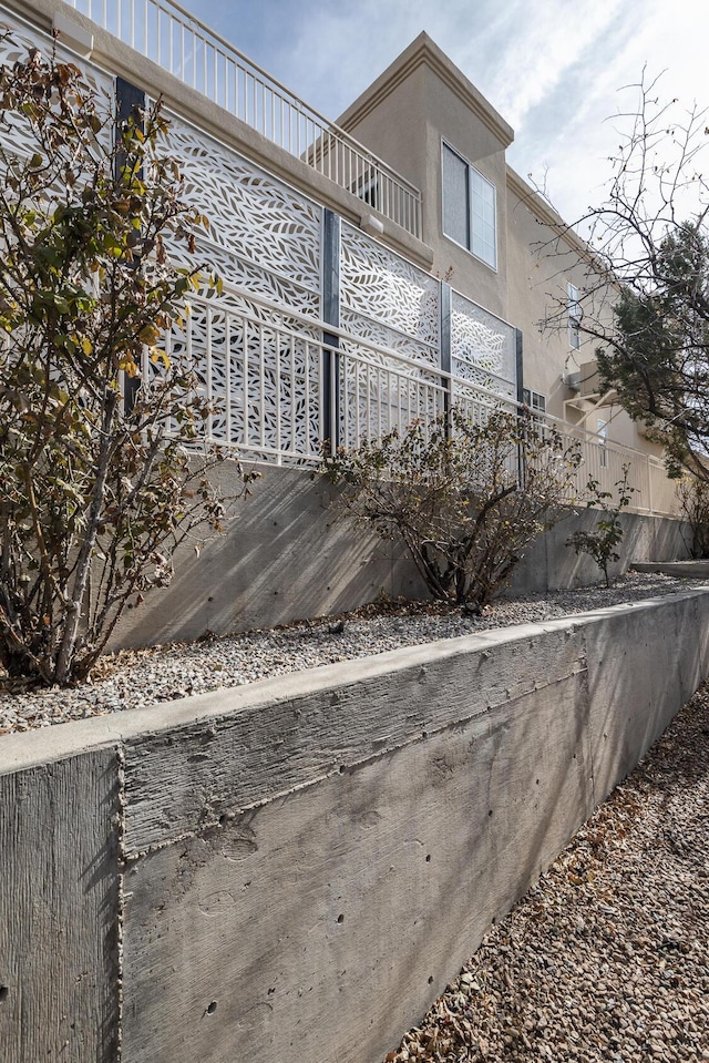 view of property exterior featuring a balcony, fence, and stucco siding