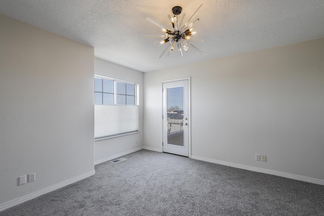 carpeted spare room featuring baseboards, visible vents, a chandelier, and a textured ceiling