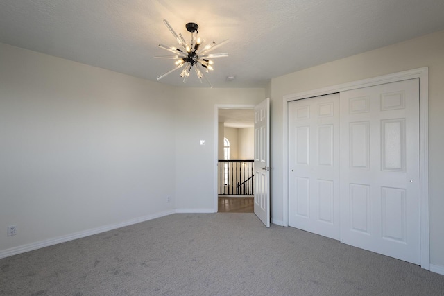 unfurnished bedroom featuring a textured ceiling, carpet floors, a closet, and baseboards