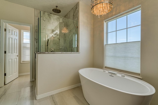 bathroom featuring a textured ceiling, a freestanding bath, a marble finish shower, and baseboards