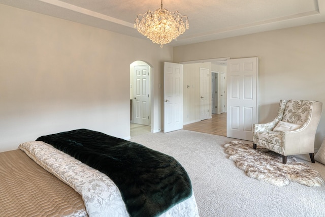 bedroom featuring arched walkways, carpet floors, and an inviting chandelier