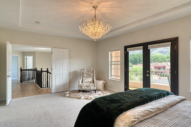 carpeted bedroom with a textured ceiling, baseboards, access to outside, french doors, and a tray ceiling