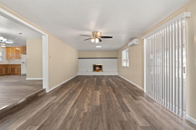 unfurnished living room featuring dark wood-style floors, ceiling fan, a brick fireplace, and a wall mounted air conditioner