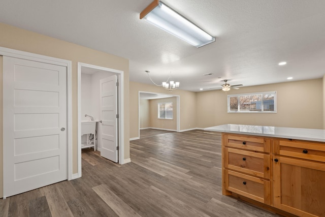 interior space with a textured ceiling, recessed lighting, ceiling fan with notable chandelier, wood finished floors, and baseboards