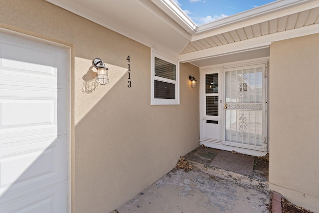 property entrance featuring an attached garage and stucco siding