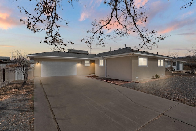 view of front facade featuring an attached garage, roof mounted solar panels, concrete driveway, and stucco siding