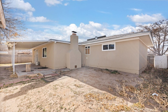 back of house with a chimney, fence, a patio, and stucco siding