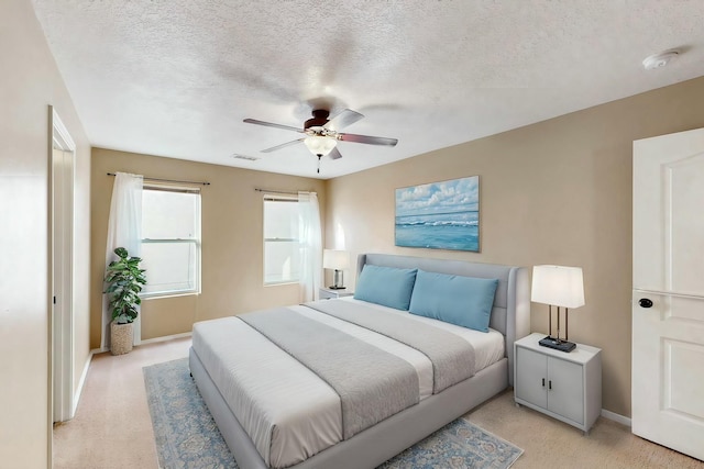 carpeted bedroom with ceiling fan and a textured ceiling