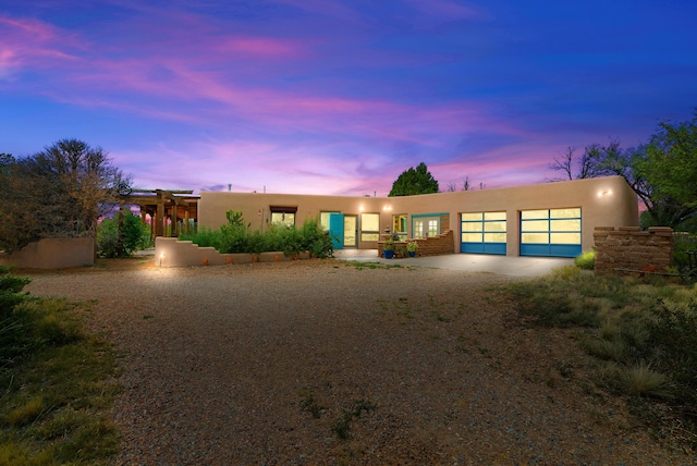 adobe home with driveway, an attached garage, and stucco siding