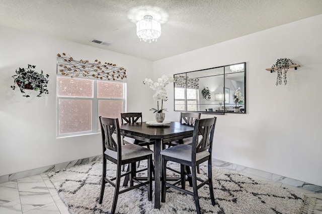 dining space with a textured ceiling and a chandelier