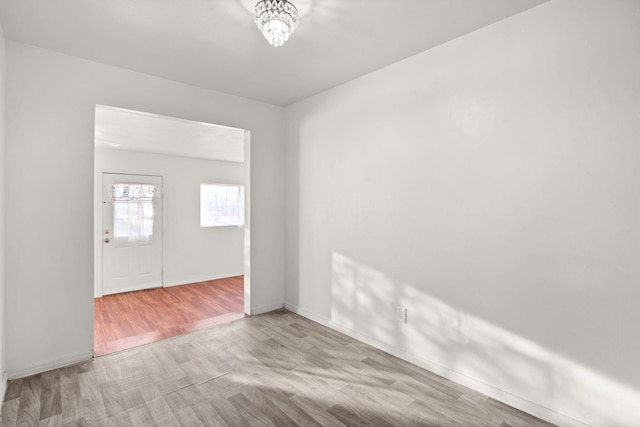 spare room featuring a notable chandelier and light hardwood / wood-style flooring