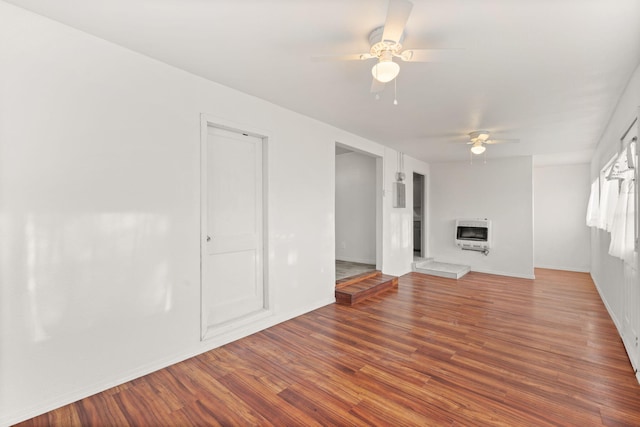 unfurnished living room featuring wood-type flooring, heating unit, and ceiling fan