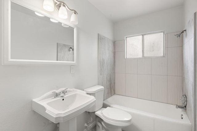 full bathroom featuring tiled shower / bath, toilet, and sink