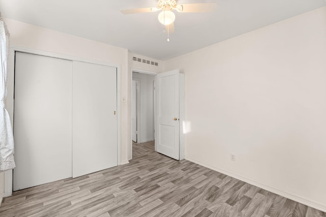 unfurnished bedroom with ceiling fan, light wood-type flooring, and a closet