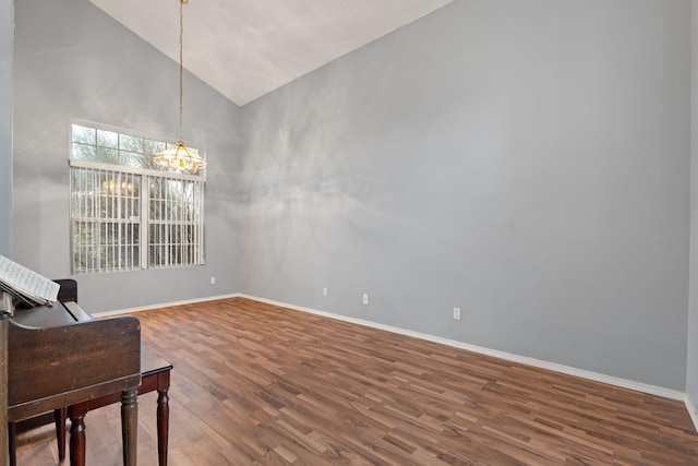 empty room with lofted ceiling, hardwood / wood-style floors, and a notable chandelier