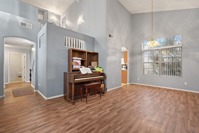 interior space with hardwood / wood-style floors, a notable chandelier, and a high ceiling