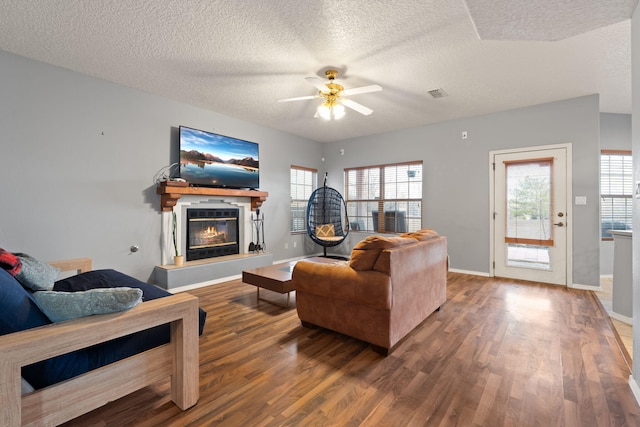 living room with ceiling fan, wood-type flooring, and a textured ceiling