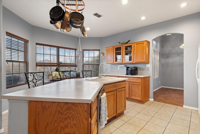 kitchen with a kitchen island with sink, sink, light tile patterned floors, and stainless steel dishwasher