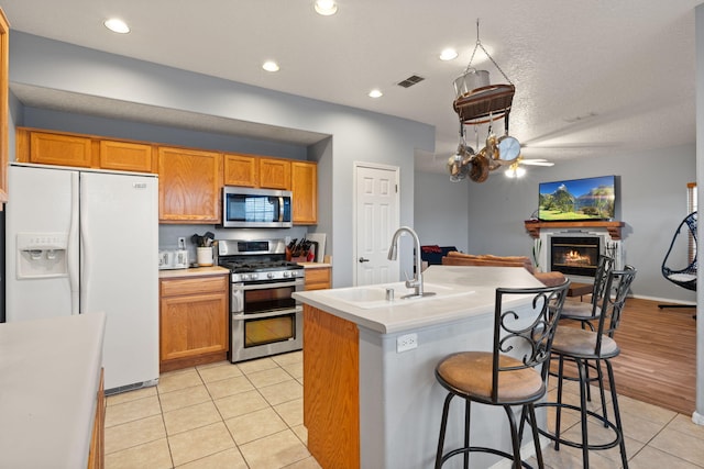 kitchen featuring sink, stainless steel appliances, an island with sink, and light tile patterned flooring