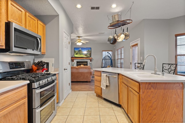 kitchen featuring appliances with stainless steel finishes, sink, a kitchen island with sink, light tile patterned floors, and a textured ceiling