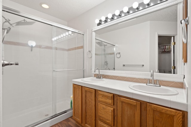 bathroom featuring vanity, a textured ceiling, and walk in shower