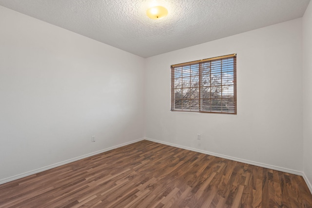 empty room with dark hardwood / wood-style floors and a textured ceiling