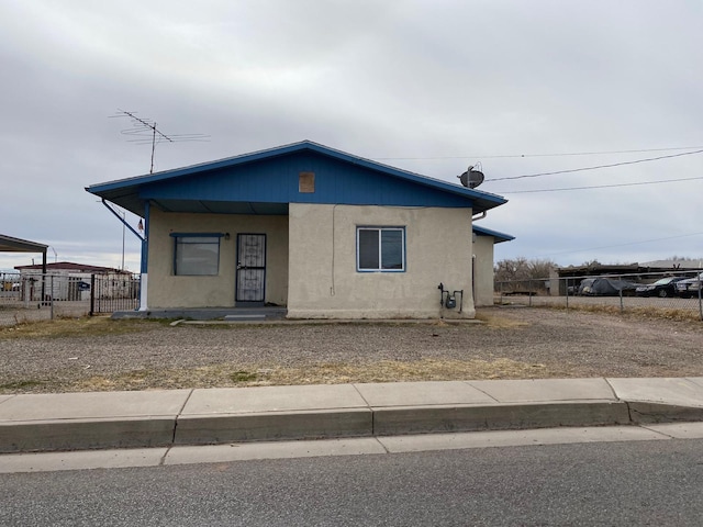 view of front facade with fence and stucco siding