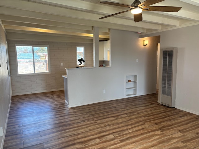 spare room with beam ceiling, hardwood / wood-style flooring, ceiling fan, and brick wall