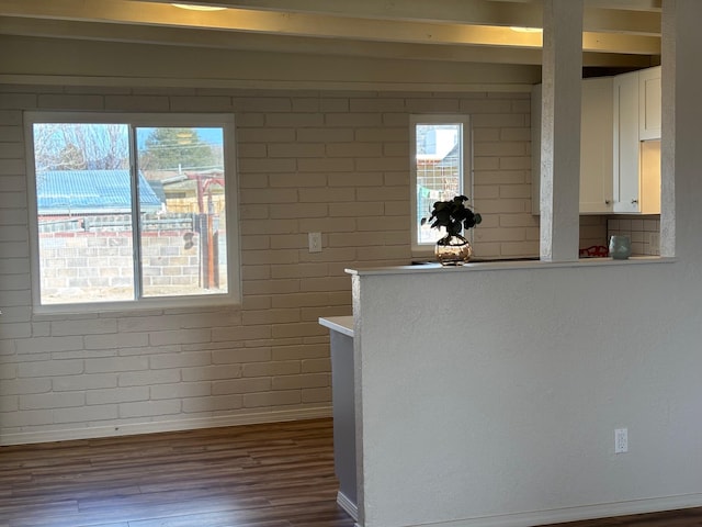 kitchen featuring hardwood / wood-style flooring, white cabinetry, and brick wall