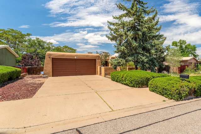 view of front of home with driveway, an attached garage, fence, and stucco siding