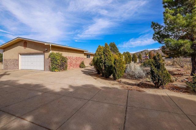 view of side of property with driveway, an attached garage, a mountain view, and stucco siding