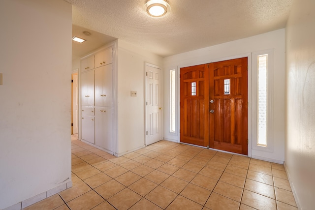 entryway featuring a textured ceiling, baseboards, and light tile patterned floors