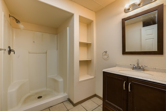 bathroom featuring a stall shower, vanity, baseboards, and tile patterned floors