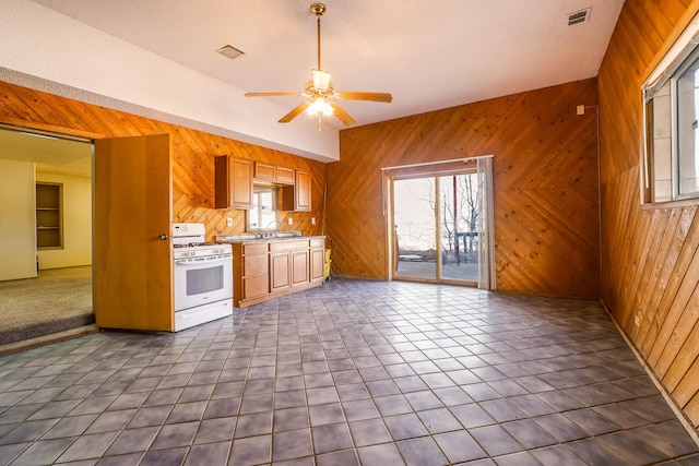 kitchen with wooden walls, light countertops, white gas stove, and visible vents