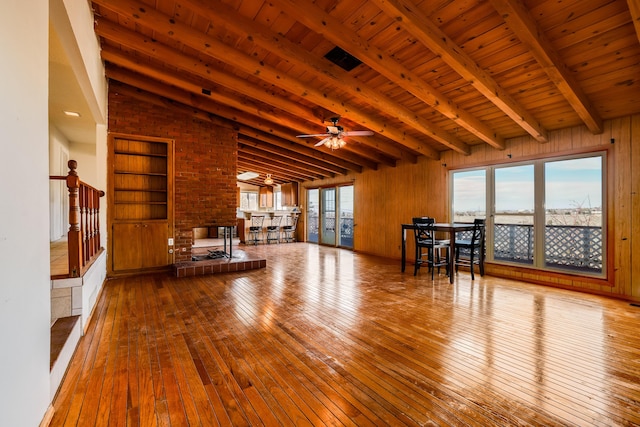 unfurnished living room with wood ceiling, wood walls, and light wood-style flooring