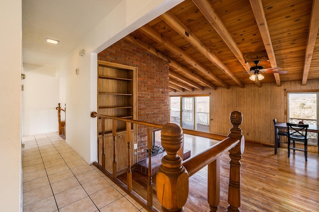 hall featuring a wealth of natural light, beamed ceiling, and an upstairs landing