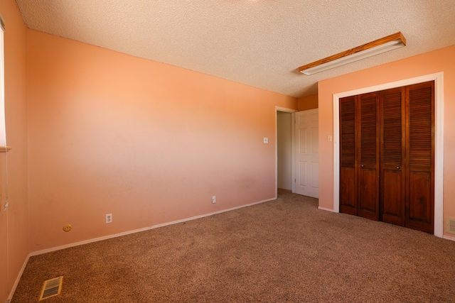 unfurnished bedroom with carpet, a closet, visible vents, and a textured ceiling