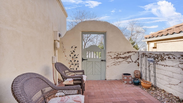 view of exterior entry featuring a gate, a patio, and stucco siding