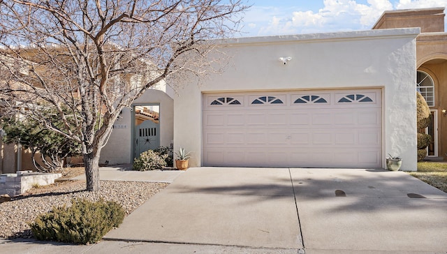 view of front of property with driveway, an attached garage, and stucco siding