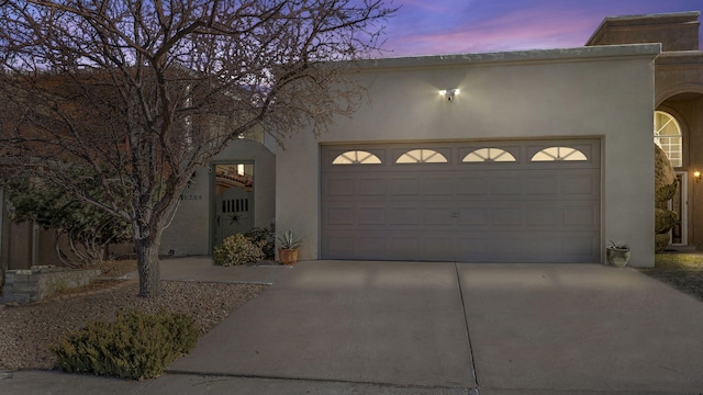 view of front of house featuring a garage, concrete driveway, and stucco siding