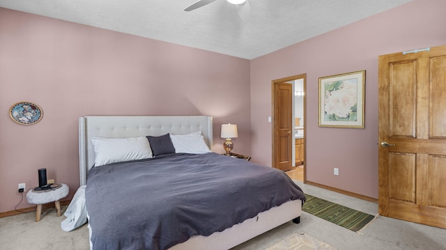 bedroom with light carpet, ensuite bath, and baseboards