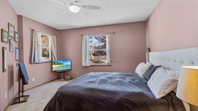 carpeted bedroom with ceiling fan, a textured ceiling, and baseboards