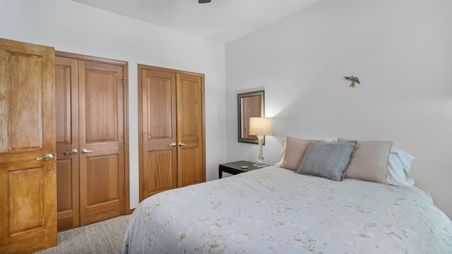 bedroom with ceiling fan, two closets, and carpet flooring