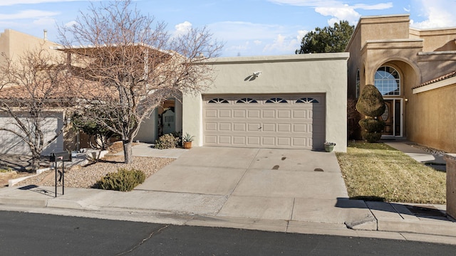 southwest-style home with concrete driveway, an attached garage, and stucco siding