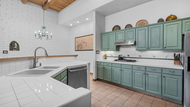 kitchen featuring tile countertops, tasteful backsplash, a sink, under cabinet range hood, and dishwashing machine