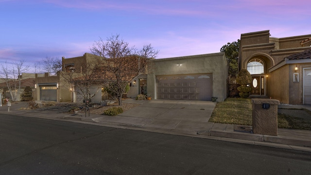 southwest-style home featuring a garage, driveway, and stucco siding