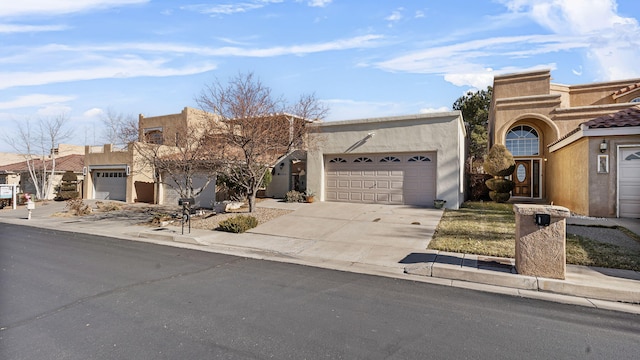 pueblo-style home featuring concrete driveway, an attached garage, and stucco siding