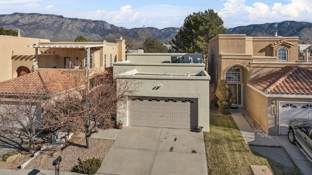 view of front of house with driveway, an attached garage, a mountain view, and stucco siding