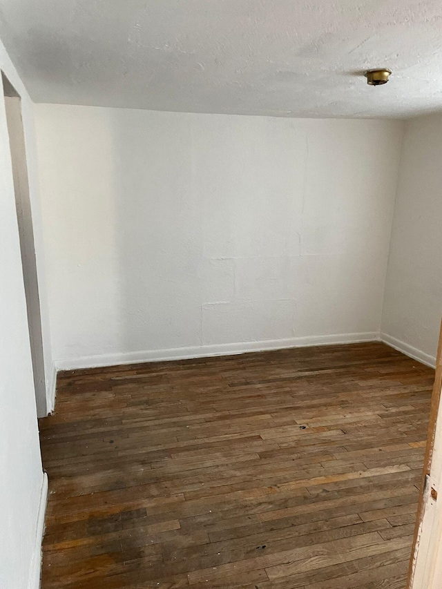 unfurnished room with dark wood-type flooring and a textured ceiling